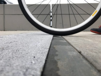 Photo of a bicycle wheel taken from close to the ground showing that the new plate design has a more gradual bump.