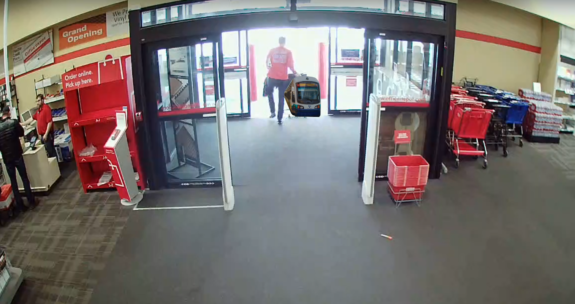 photoshop of the security footage showing Tim Eyman stealing a chair from Office Depot, except a light rail train has replaced the chair.