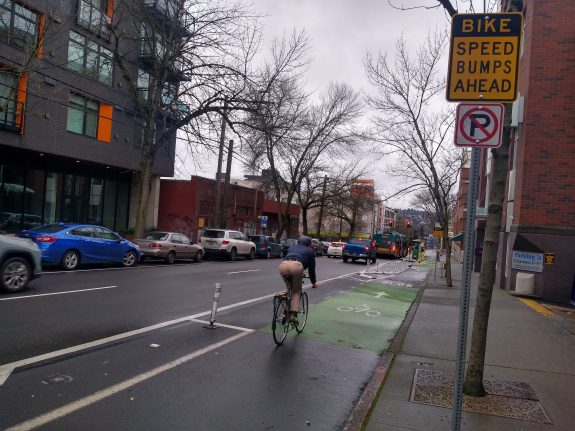 person biking along next to advance warning sign for Bike Speed Humps Ahead
