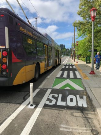 A bus stops at a bus stop next to the bike lane. 