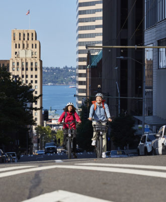 Photo of two people biking up a steep hill in downtown Seattle.