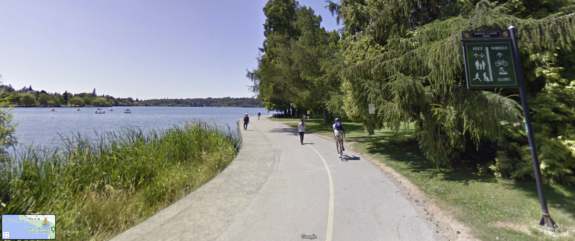 Photo of people walking and biking on the path next to the lake. 