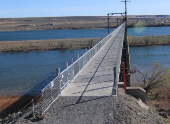 Photo of a long trail bridge crossing the river.