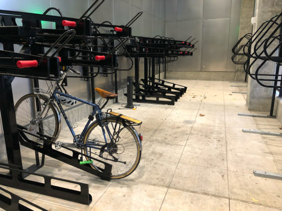 One bicycle in a room full of empty bike racks.