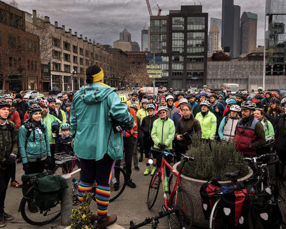 A large group of people with bikes listen to a speaker in Pioneer Square.