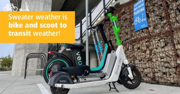 Scooters and bikes parked inside a painted box with text "Sweater weather is bike and scoot to transit weather!"
