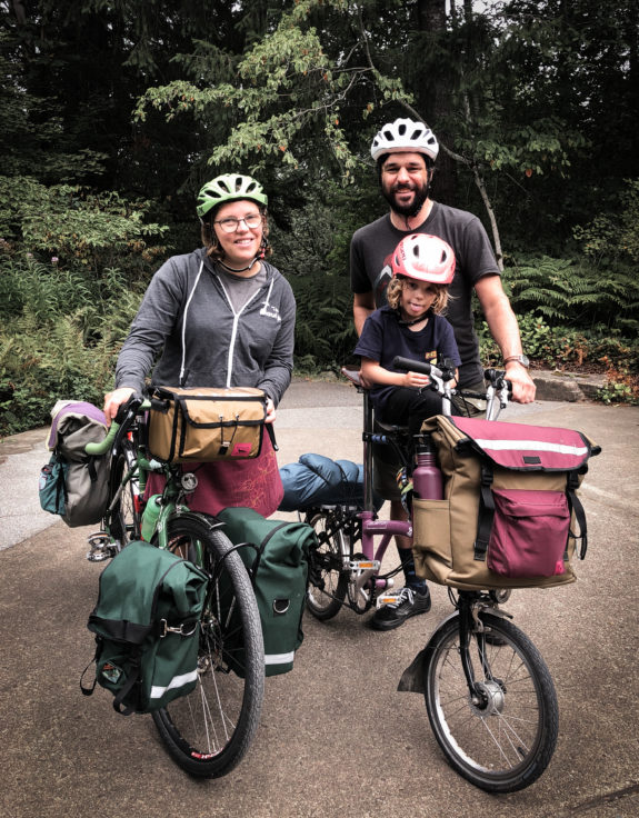 Photo of two adults with bikes loaded with camping gear. The author's bike is a Brompton that is also carrying a child.