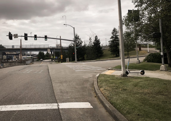 A crosswalk connects a path across a roadway ramp.