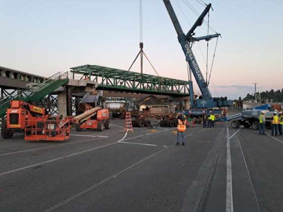 Photo from roadway level of a crane moving a span into place.