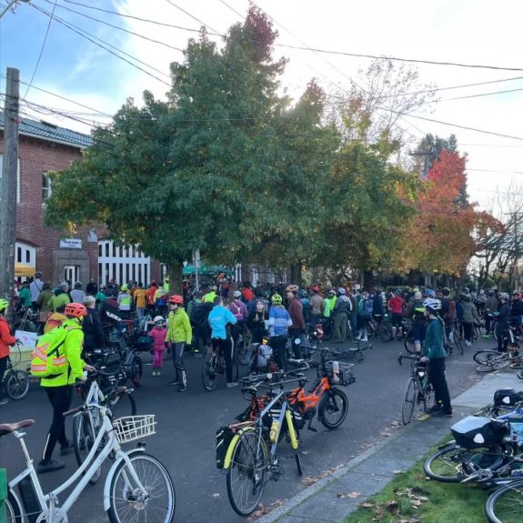 Wide photo of a large group of people with bikes gathered outside Byrd Barr Place.