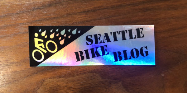 Seattle Bike Blog logo in black on a silvery background that changes colors in the light.