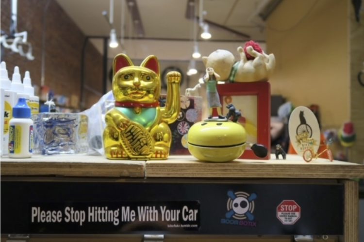 Photo of the counter in the shop with a cat statue and a sticker that says shot hitting me with your car.
