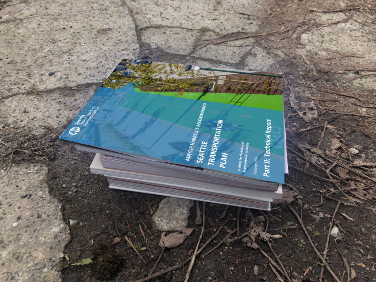 Photo of a heavy stack of papers on smashed concrete with the seattle transportation plan cover on top.